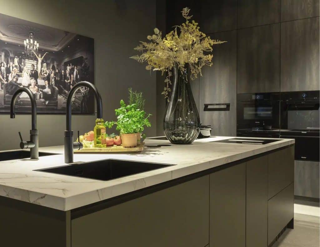 Impressie van een keuken met groene wanden, kasten en kookeiland.