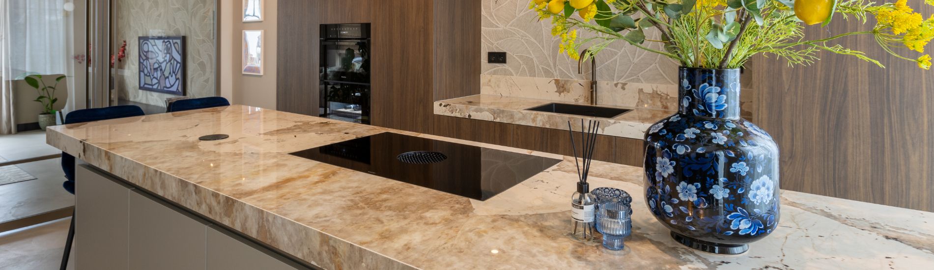 Impressie van een keuken met walnoot kastenwand en eiland met dekton khalo werkblad