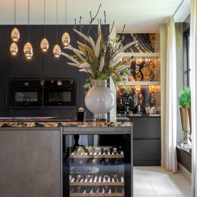 Impressie van een trendy luxe keuken met eiland, voorzien van bronzen accenten en een werkblad in aardse tinten.