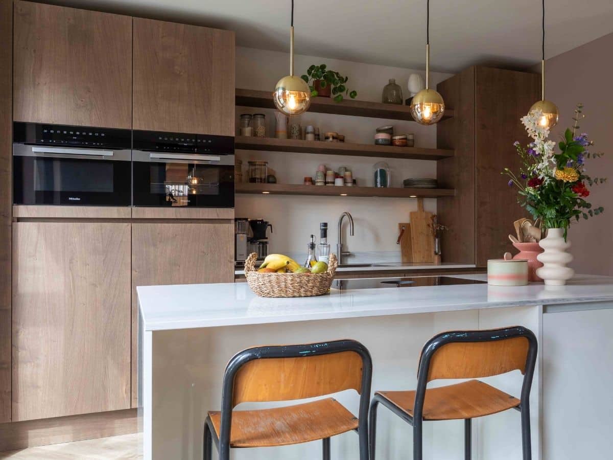 Impressie van een trendy luxe keuken met eiland, voorzien van bronzen accenten en een werkblad in aardse tinten.