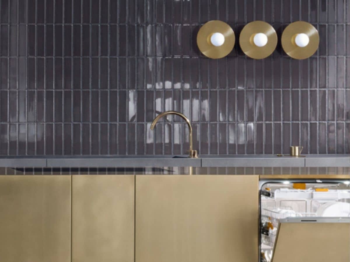 Impressie van een two-tone keuken met hoogglans zwarte wandtegels en aanrecht in de kleur brons.