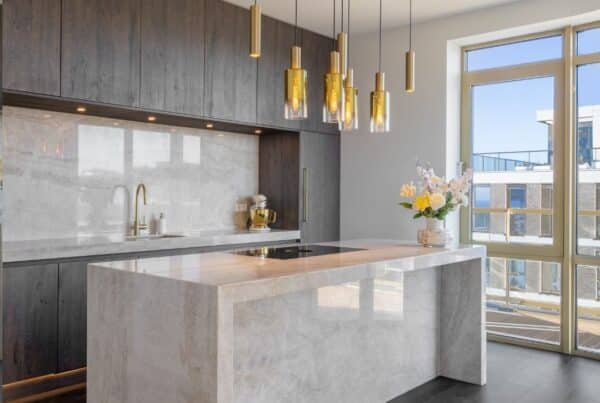 Impressie van een luxe keuken, voorzien van glanzend marmer met gouden aders, dat we terugzien als aanrechtblad, de achterwand van een nis en het kookeiland.