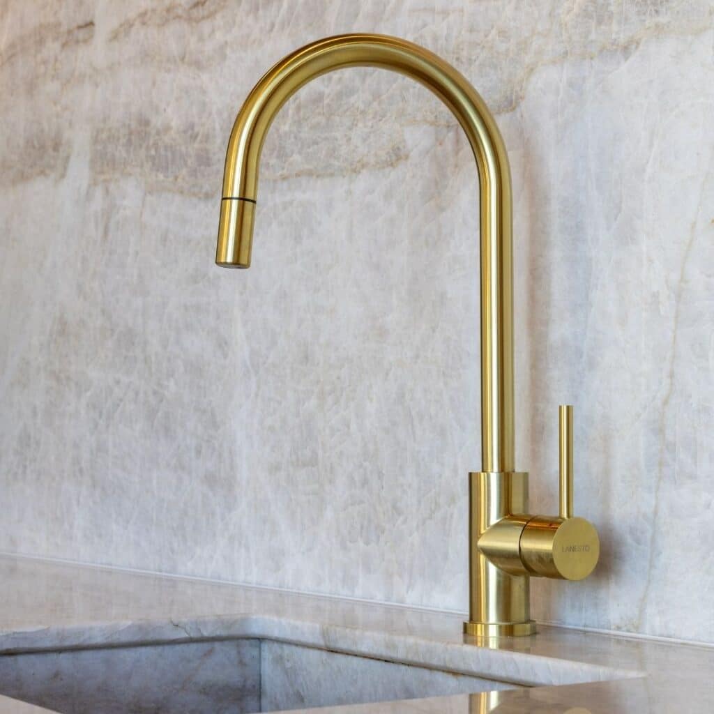 Close-up van een gouden Quooker, geplaatst op een glanzend marmer blad.