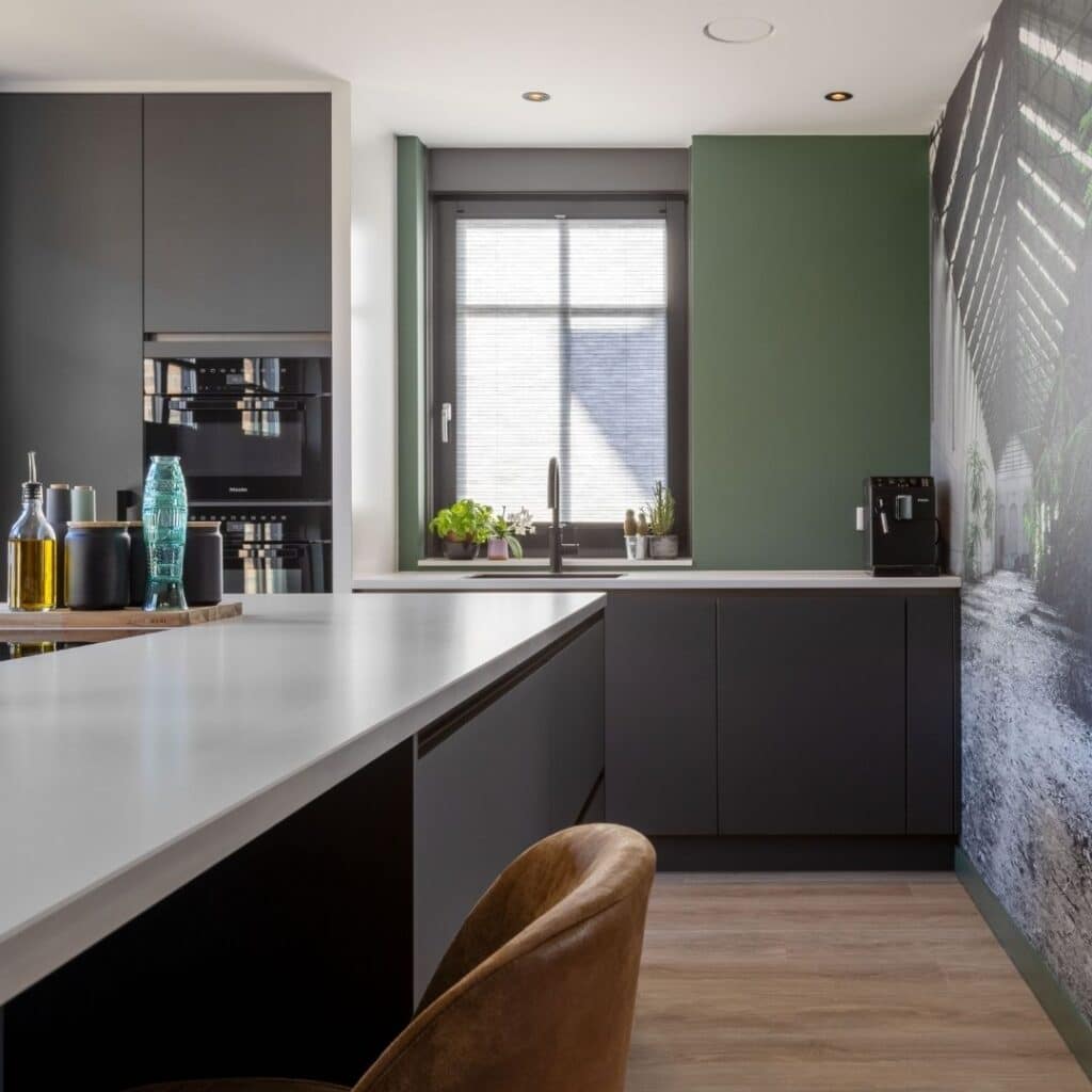 Impressie van een moderne keuken, voorzien van een zwart kookeiland met zitgedeelte, een zwarte kastenwand en aardse kleuren.