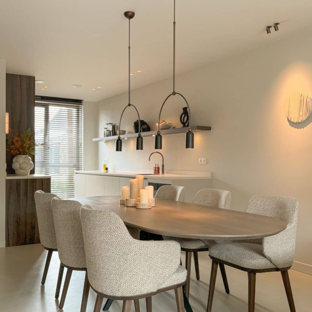 Impressie van een benedenverdieping met een Japandi keuken in een parallel opstelling. De keuken is ingericht met een strak werkblad, veel opberglades, een Quooker, een wijnklimaatkast en houten kastenwand.