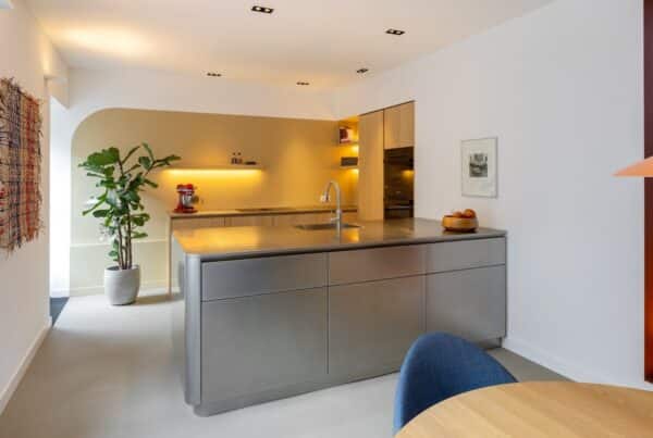 Impressie van een design keuken, voorzien van houten kasten, een RVS schiereiland en sfeervolle verlichting en decoraties.