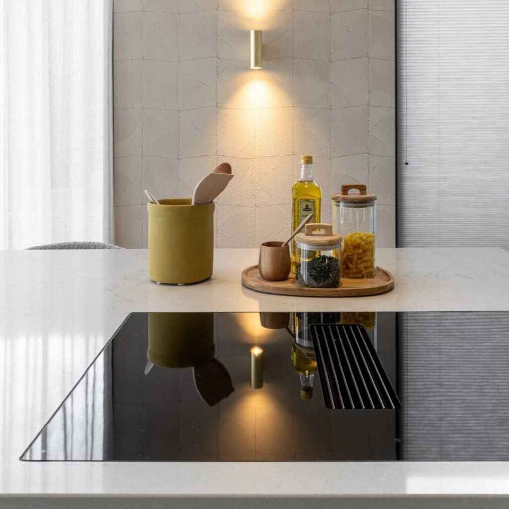 Close-up van een kookplaat met werkbladafzuiging, op een kookeiland met natuursteenlook werkblad.