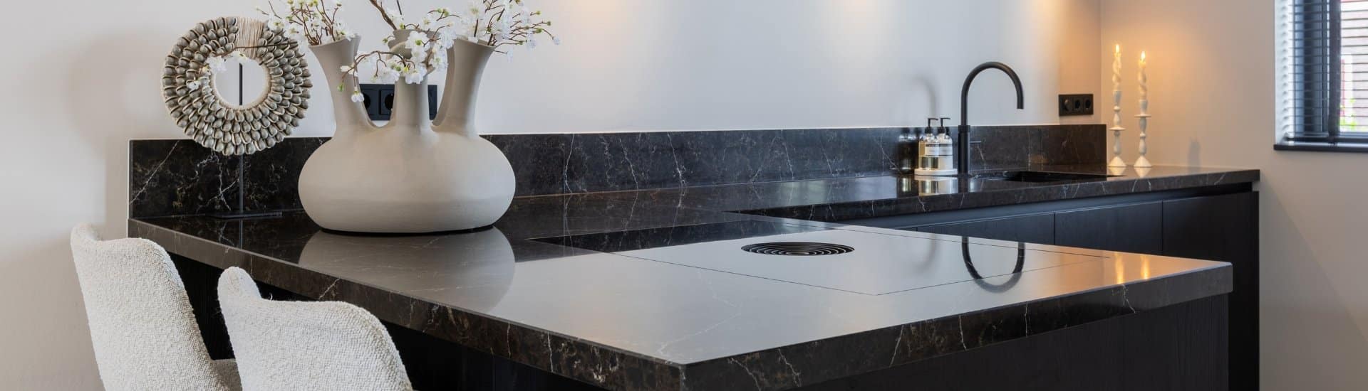 Impressie van een moderne hoekkeuken met een werkblad in zwart marmerlook.