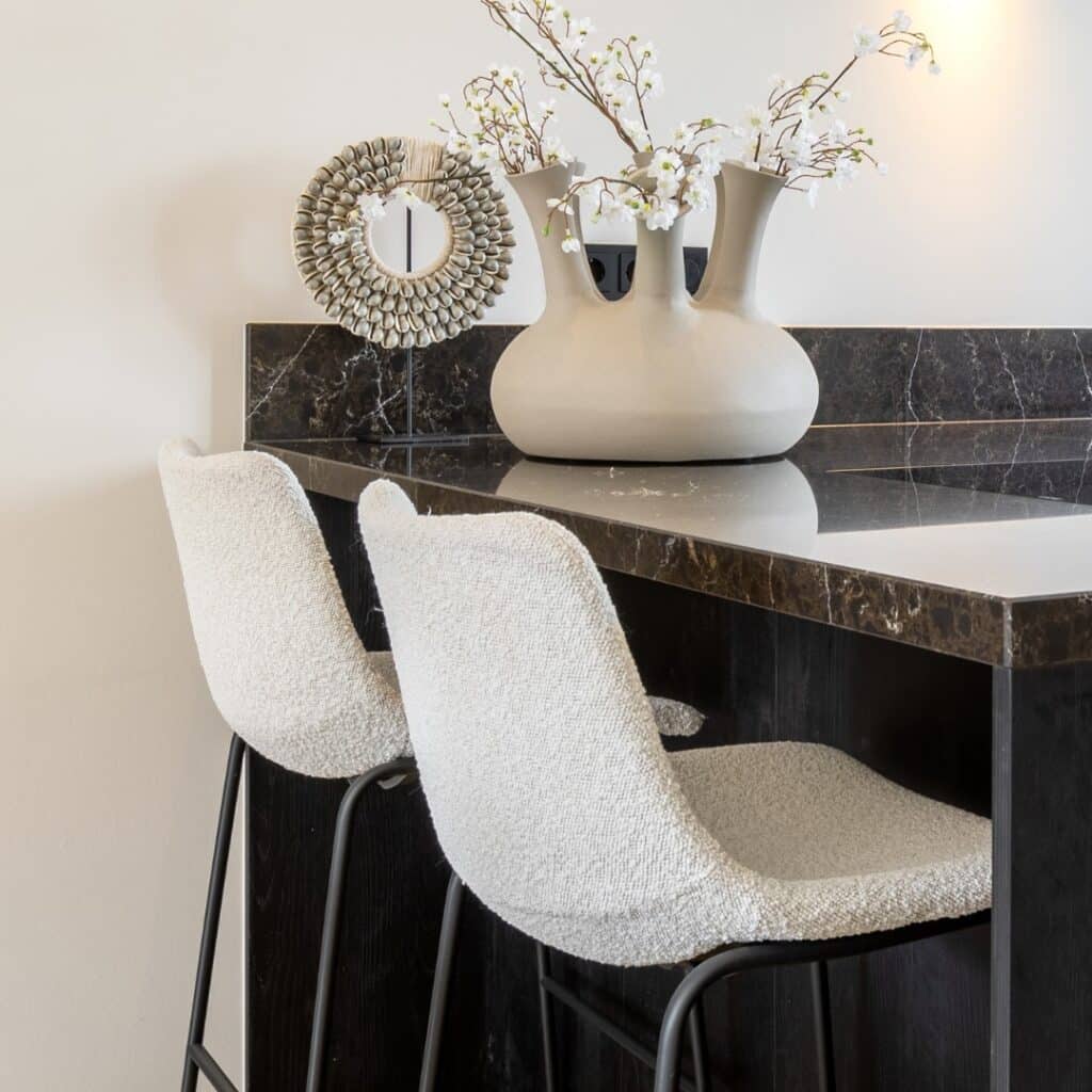 Impressie van een moderne hoekkeuken, voorzien van een zitgedeelte met twee barstoelen.