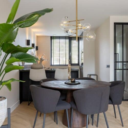 Uitzicht vanuit de woonkamer van een nieuwbouwwoning naar een moderne hoekkeuken met bar.