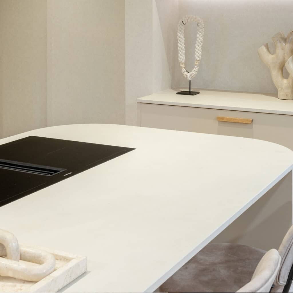 Impressie van een wit kookeiland met ronde hoeken en een Miele kookplaat met werkbladafzuiging.