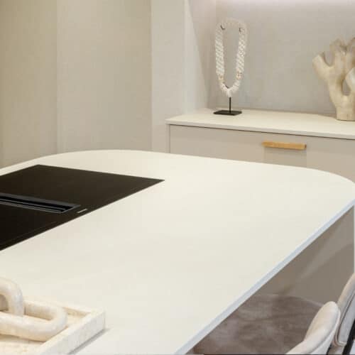 Impressie van een wit kookeiland met ronde hoeken en een Miele kookplaat met werkbladafzuiging.