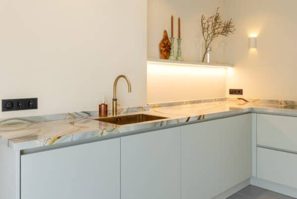 Impressie van een luxe keuken met marmer werkblad en kraan in geborsteld messing.