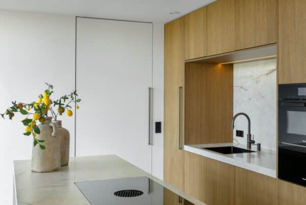 Impressie van een keuken met licht eiken kastenwand en kookeiland met marmerlook blad.