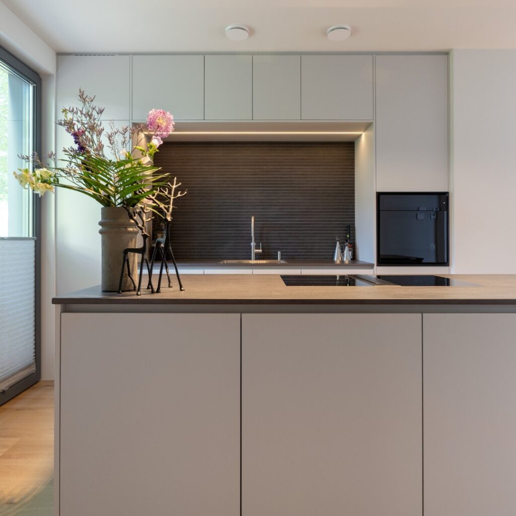 Impressie van een strakke moderne keuken met nis en kookeiland.