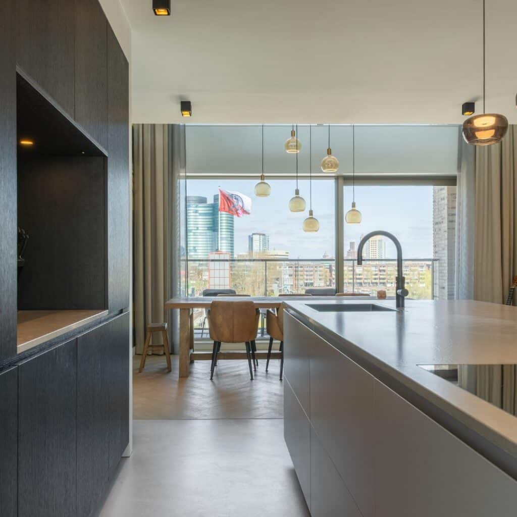 Impressie van een zwart-wit keuken met kookeiland en kastenwand met nis.