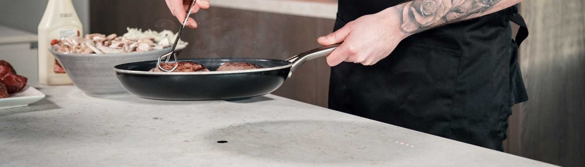 Een kok is aan het bakken op de Novy Undercover, een onzichtbare kookplaat die geheel is weggewerkt in het keukenblad.